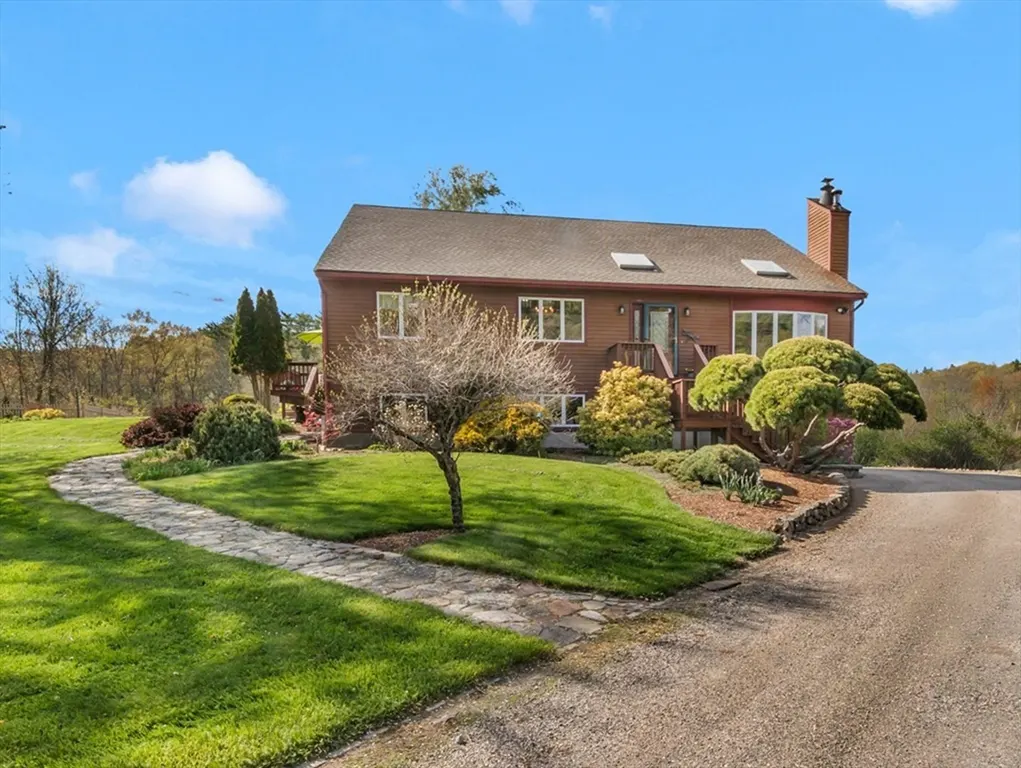 Exterior of a brown two-story house with a stone walkway, green lawn, and blue sky.