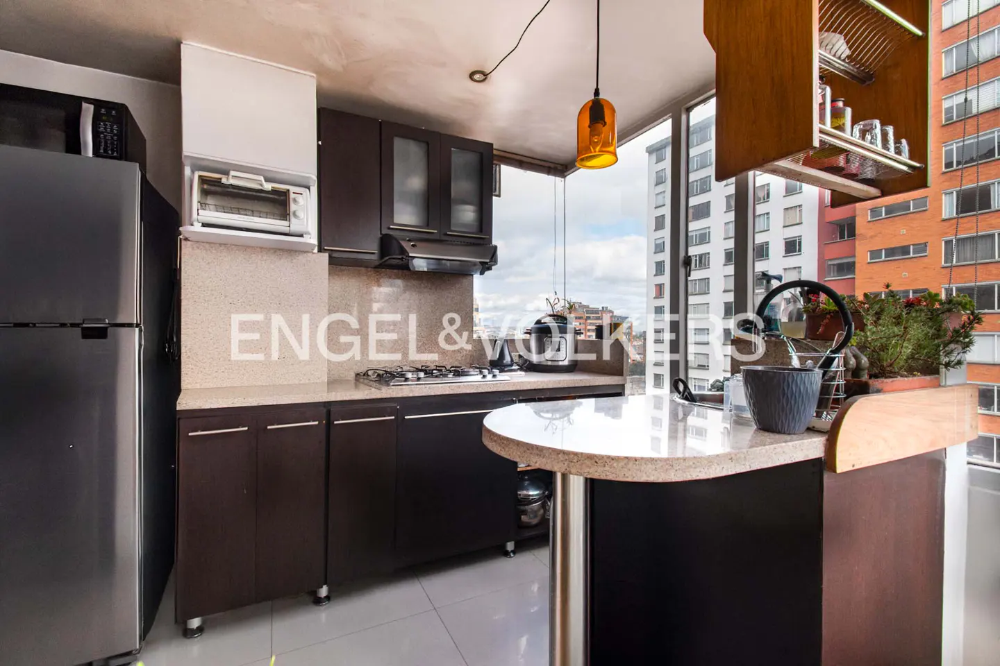 A modern kitchen with dark wood cabinets, stainless steel appliances, and a breakfast bar overlooking a city view.