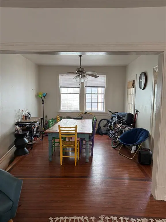 A bright dining room with hardwood floors, a colorful table and chairs, and two bicycles in the background.
