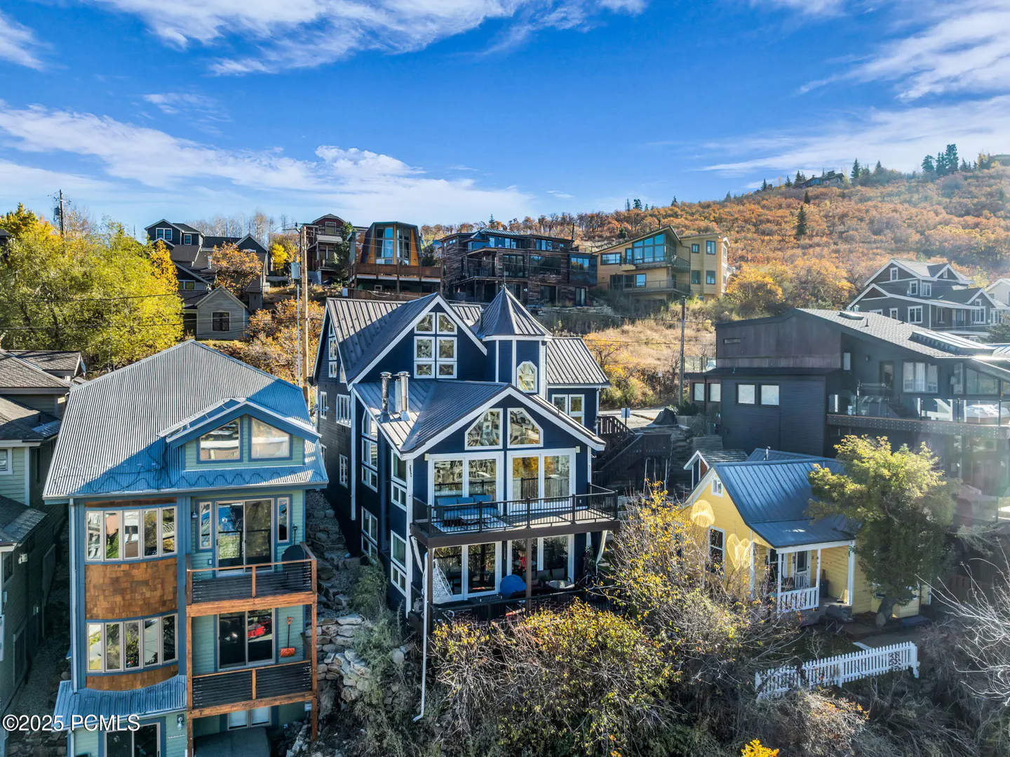Aerial view of colorful hillside homes under a blue sky with scattered clouds.