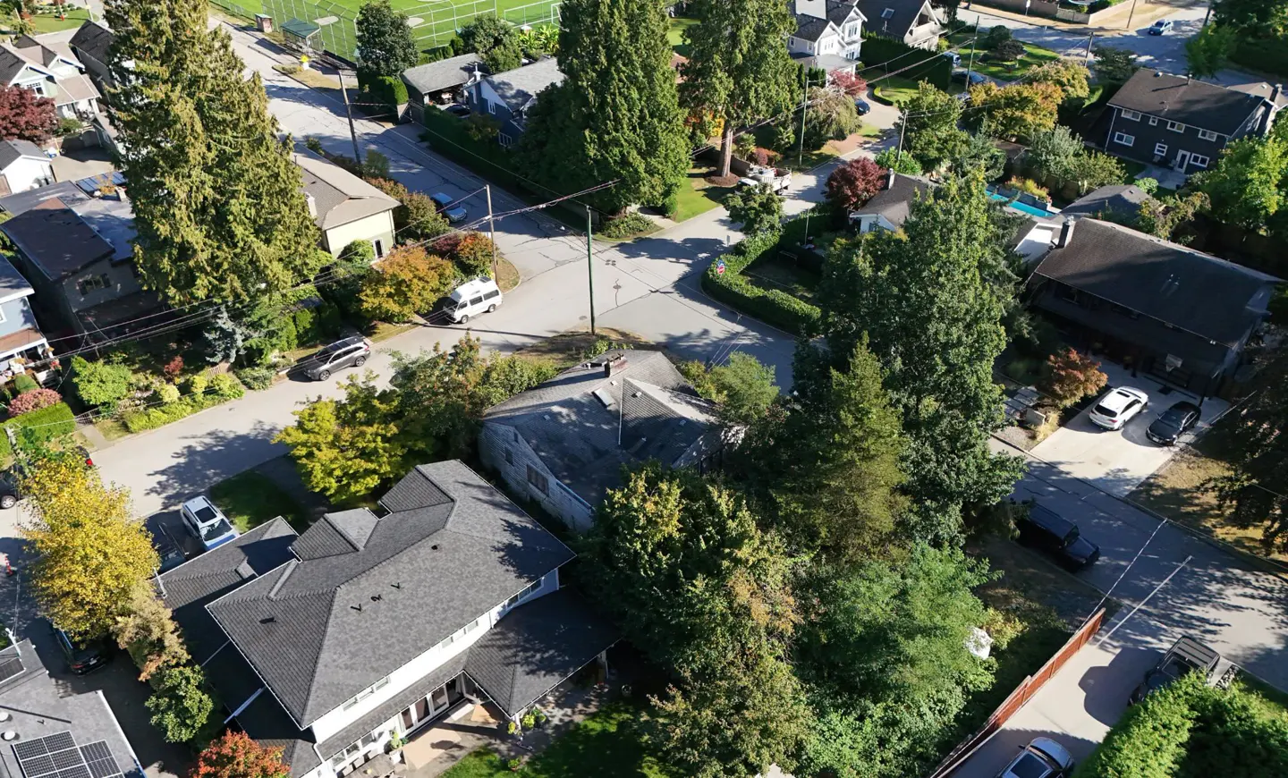 Aerial view of a residential neighborhood with houses, green trees, and cars on the streets.
