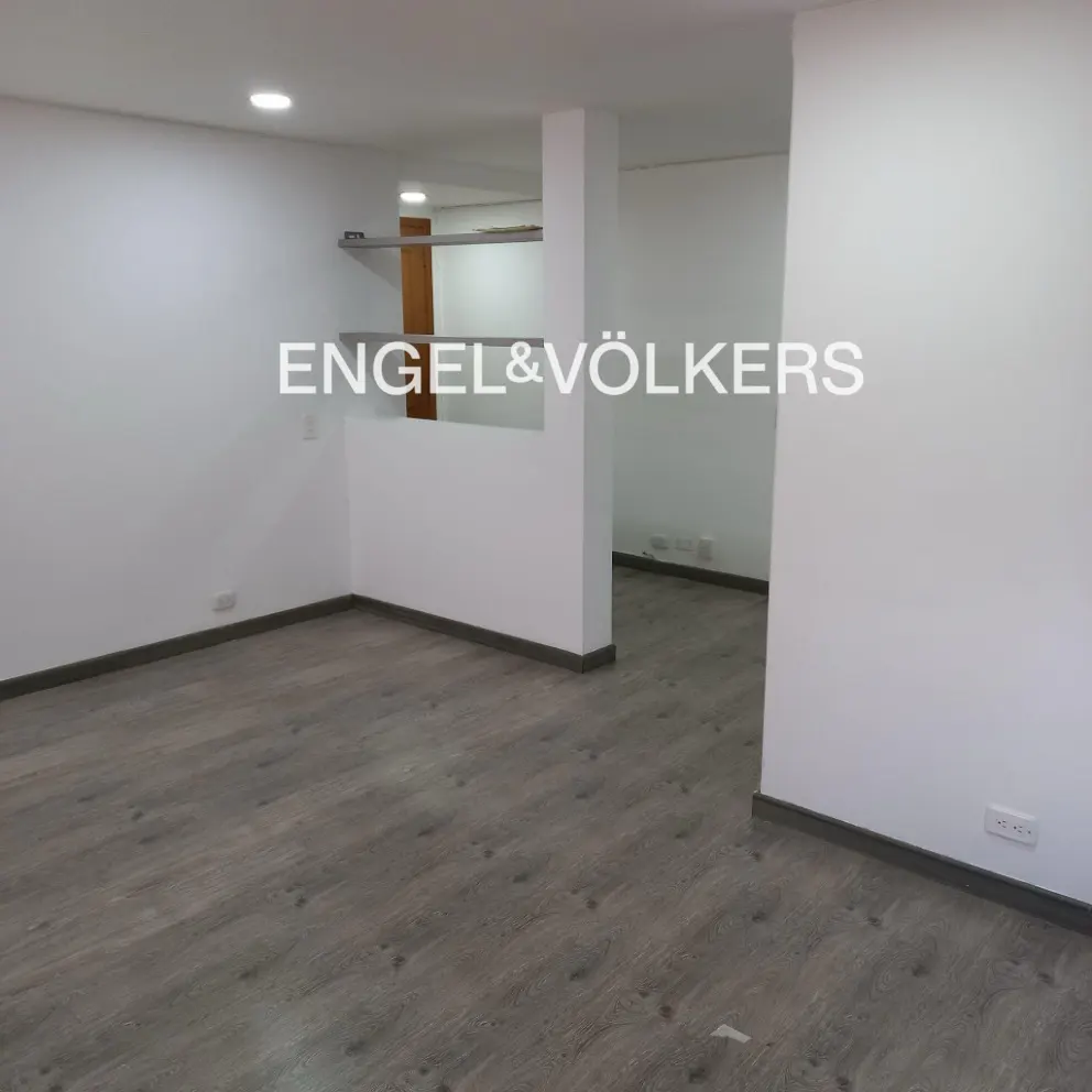 Empty room with gray wood floors and white walls. Engel & Völkers logo is superimposed on the image.