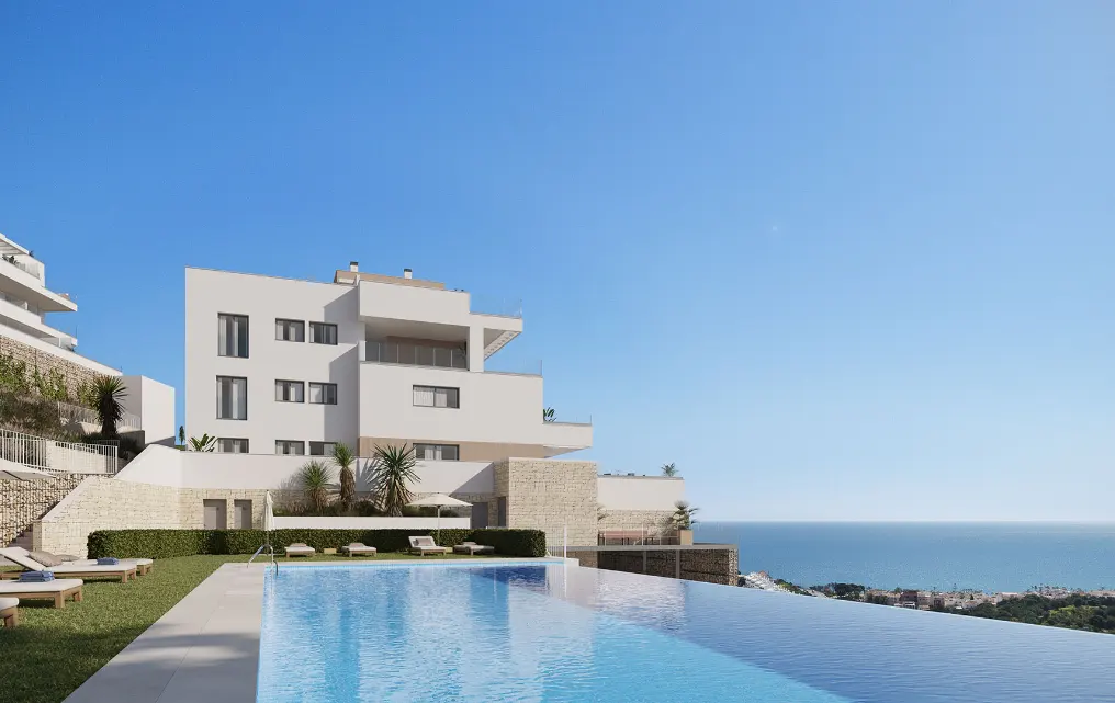 Modern white building with a blue infinity pool overlooking the ocean under a clear blue sky.
