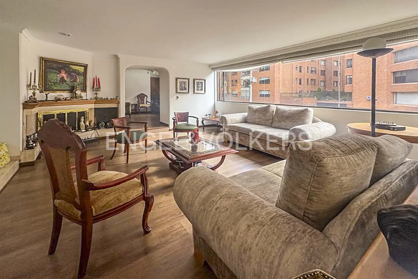 A living room with sofas, chairs, a fireplace, and a large window with a city view.