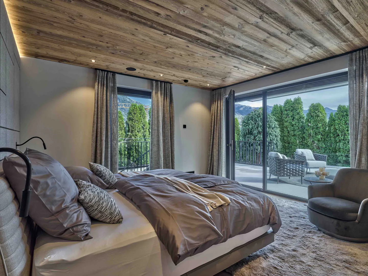 Bedroom with a wooden ceiling, a large bed, and sliding glass doors to a patio with outdoor seating.