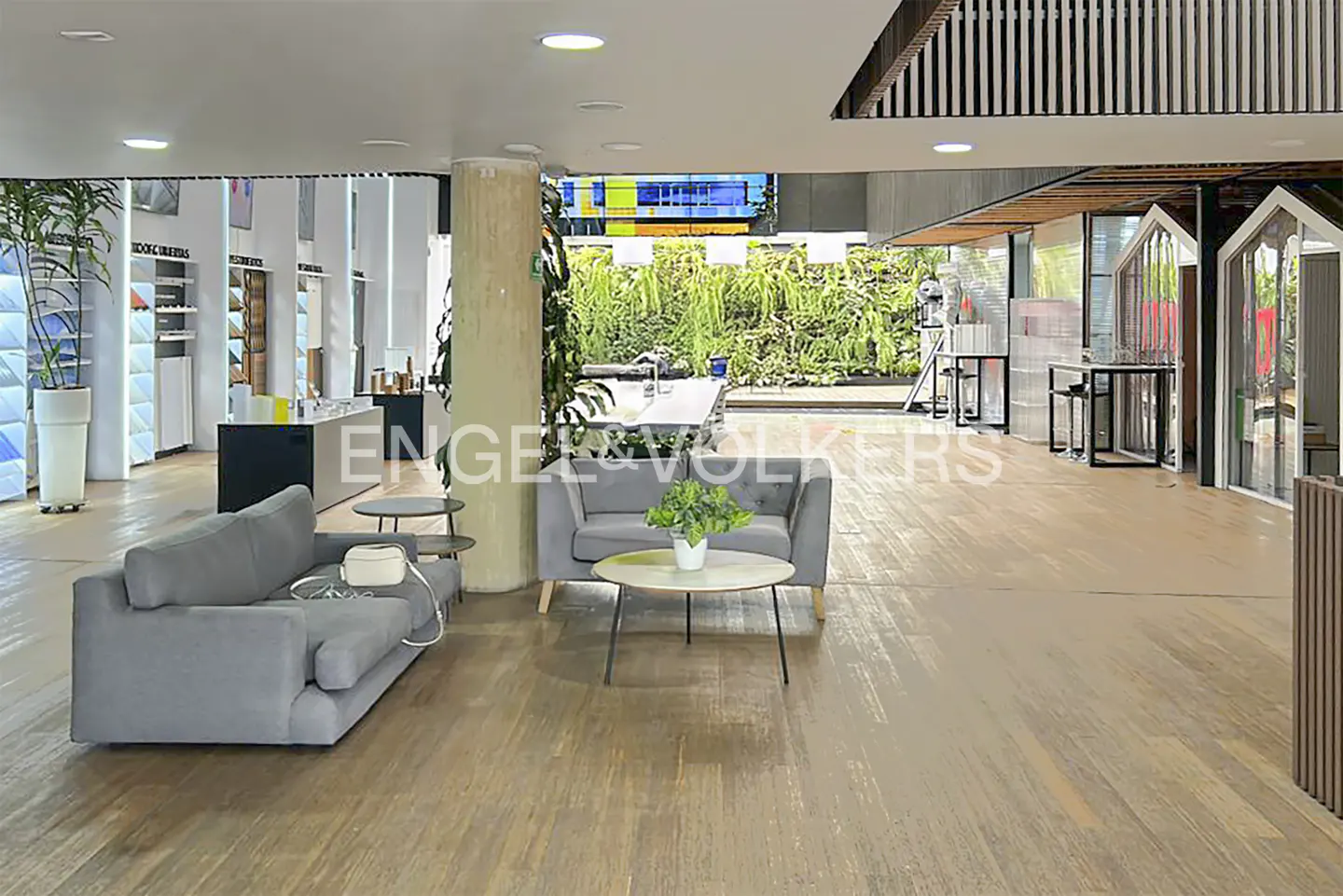 A real estate office interior with gray sofas, wood floors, and a green wall.
