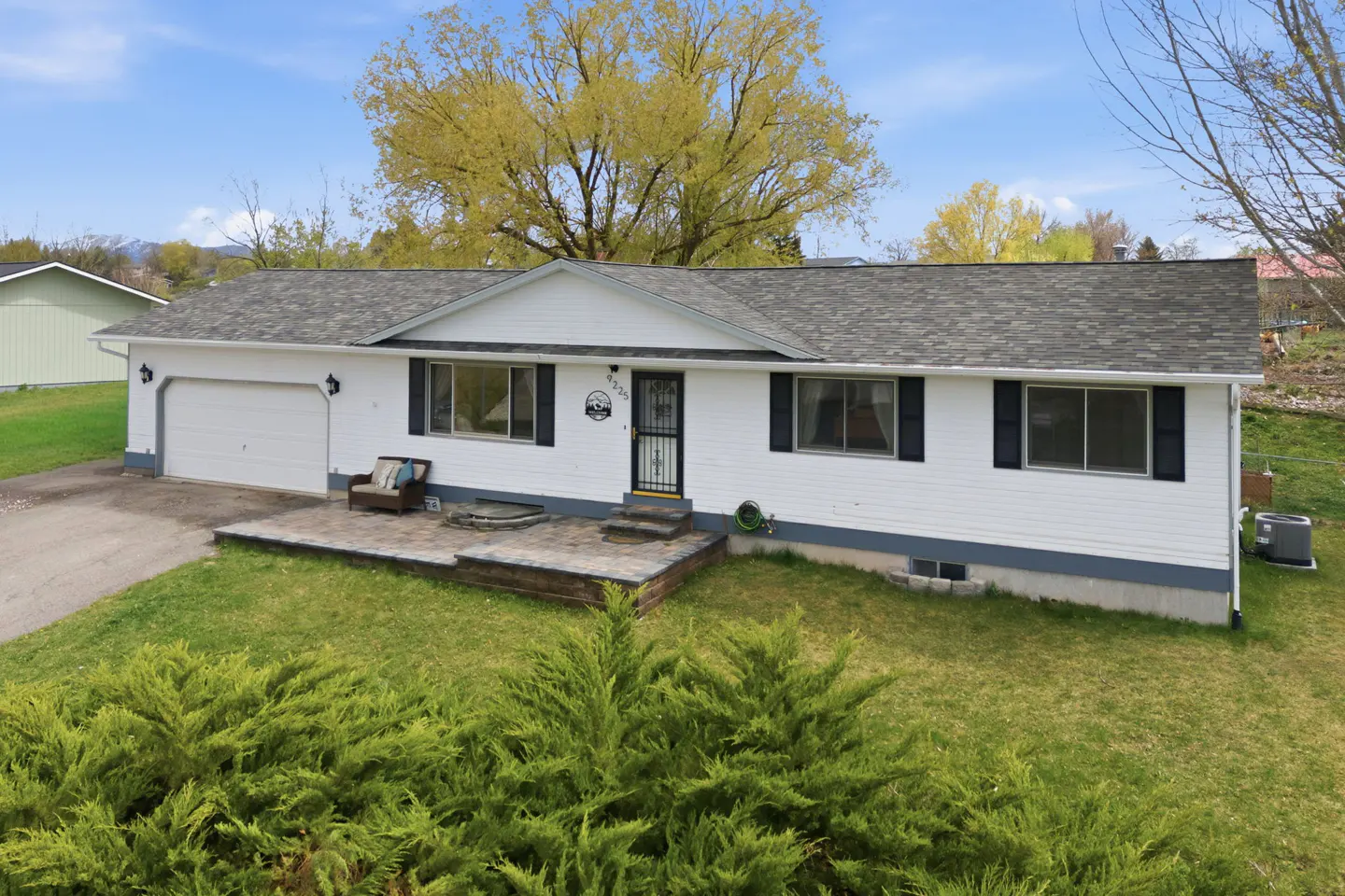 A white, one-story house with a gray roof, black shutters, and a green lawn.