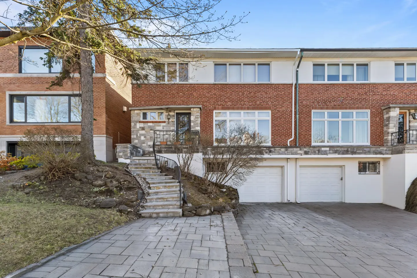 Two-story brick townhouse with white trim, a stone walkway, and a two-car garage.