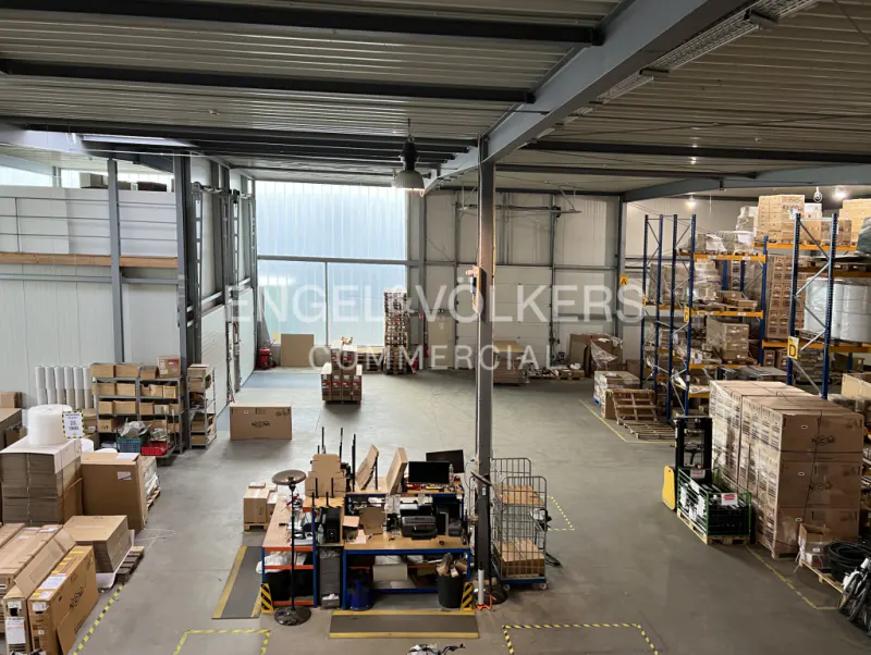A high-angle view of a large warehouse with metal shelving, boxes, and a workstation.