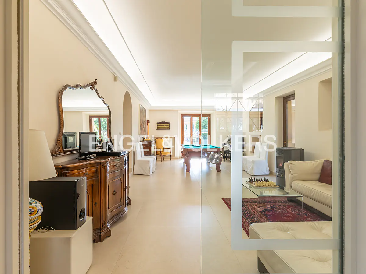 Interior view through glass doors into a spacious room with a pool table, seating, and a wooden dresser with a mirror.