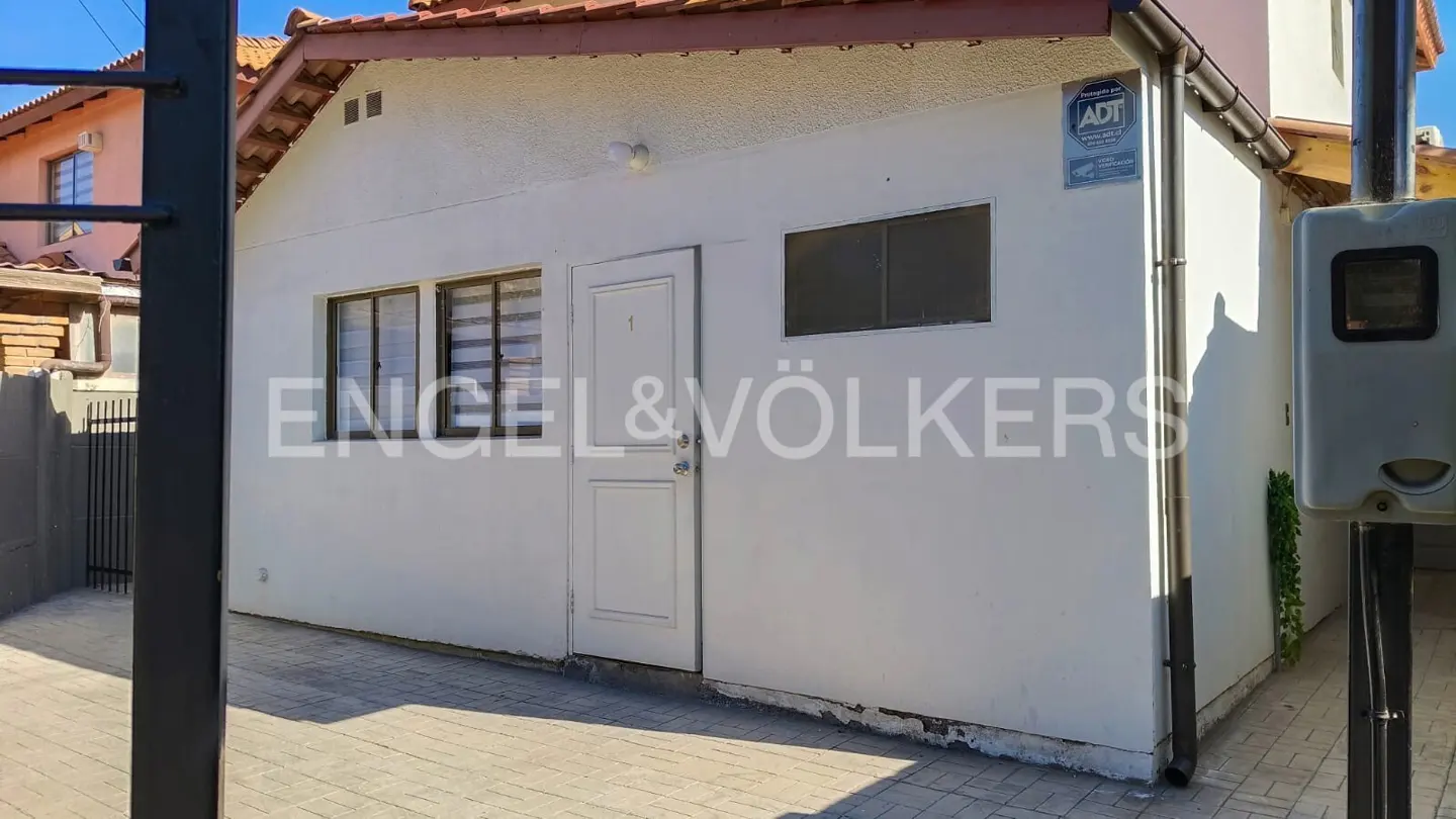 Exterior view of a white stucco house with a red tile roof, featuring windows, a door, and an ADT security sign.