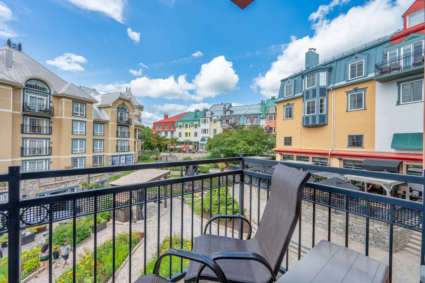 View from a balcony with a chair overlooking a courtyard with colorful buildings and a blue sky.