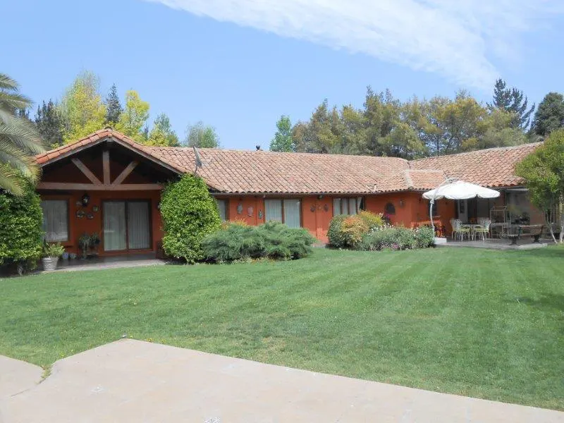 Exterior view of an orange house with a red tile roof, green lawn, and patio furniture.