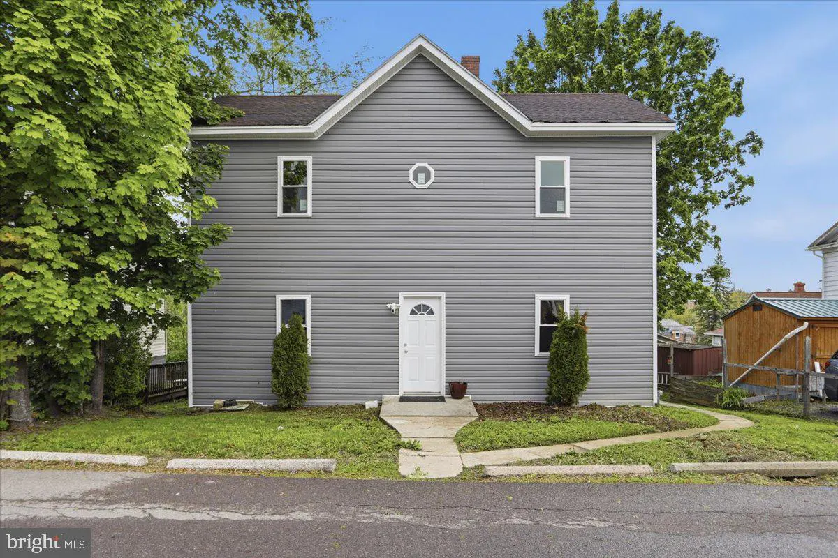 Two-story gray house with white trim, a white front door, and green trees on either side.