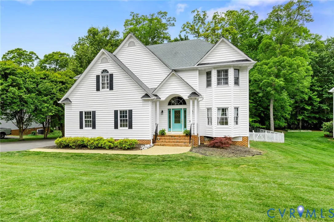 Two-story white house with a teal door, black shutters, and a green lawn. Trees are in the background.
