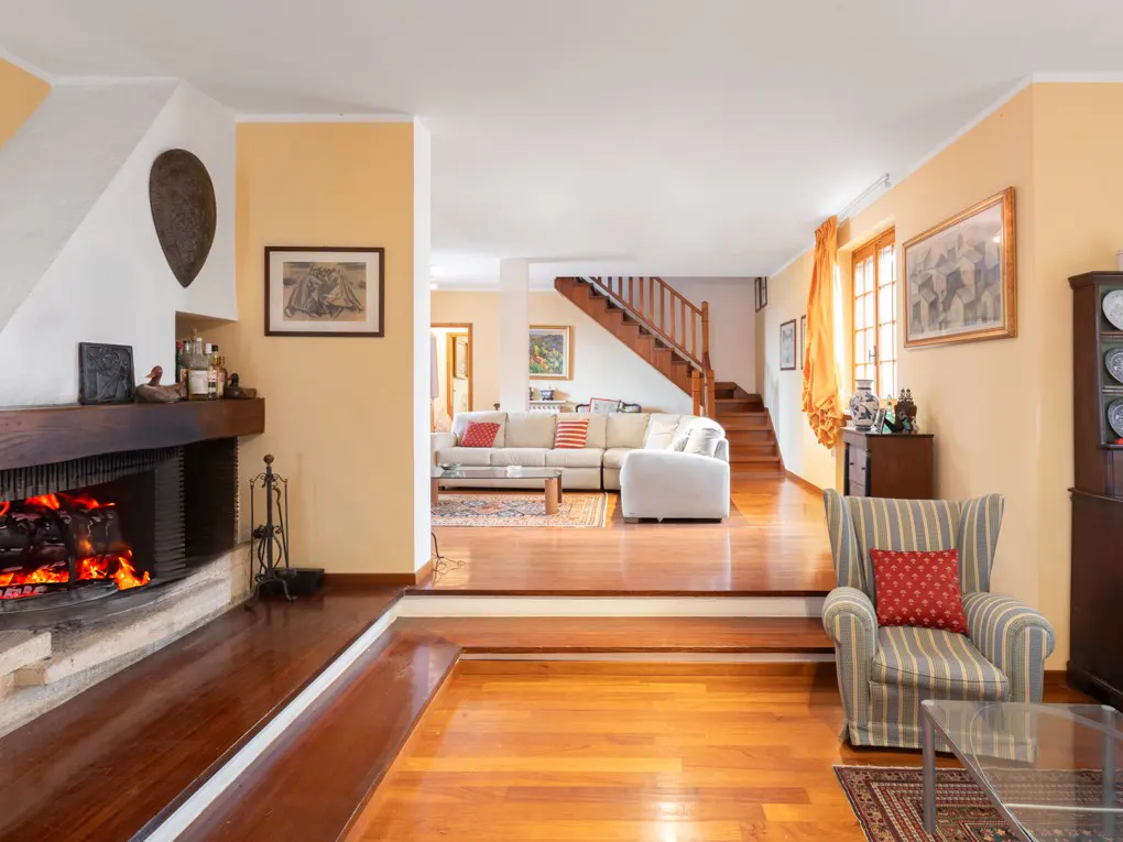 A warm living room with a fireplace, hardwood floors, and a staircase leading to the upper level.