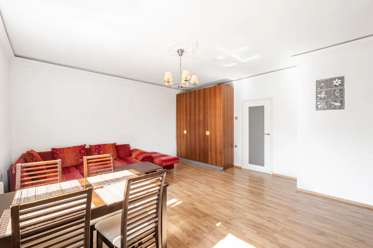 Bright living room with wood floors, a red sofa, a wooden dining set, and a large built-in wooden wardrobe.