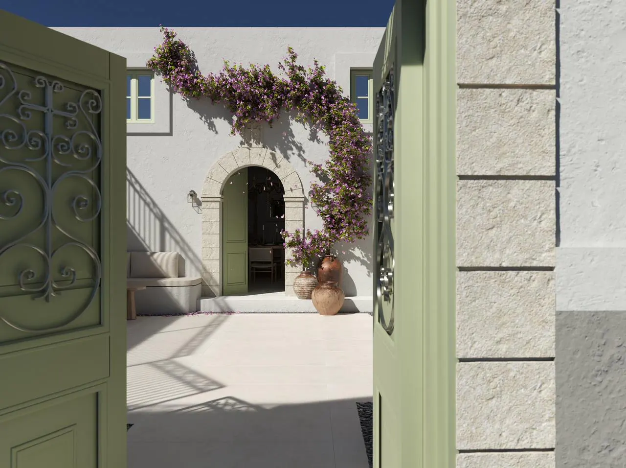 View through an open green gate to a white courtyard with stone archway and purple flowers.