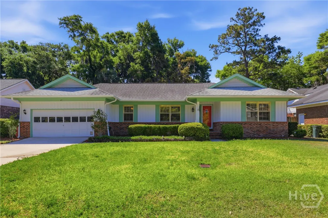 Front view of a one-story house with white siding, green trim, a red door, and a green lawn.