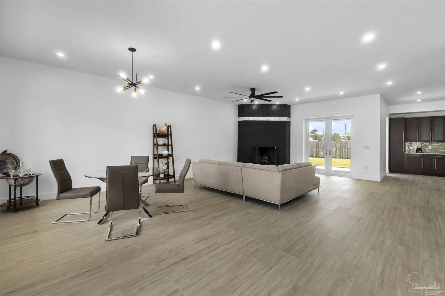 Open-concept living space with wood-look tile, a black fireplace, and a dining area with a glass table.