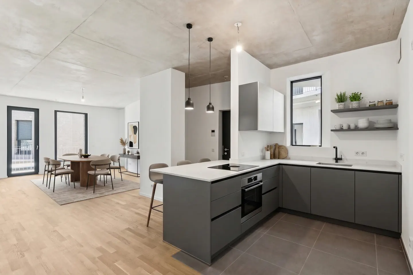 A modern kitchen with gray cabinets, white countertops, and a kitchen island. A dining area with a round table is in the background.