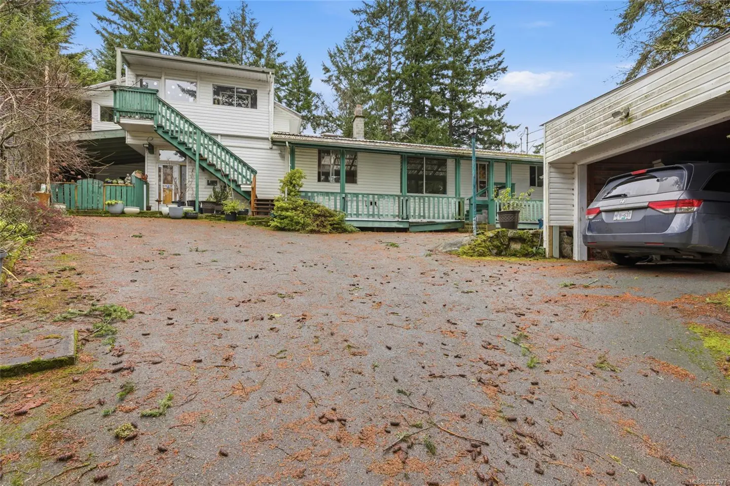 Exterior view of a two-story white house with green trim and a gray minivan parked in the garage.