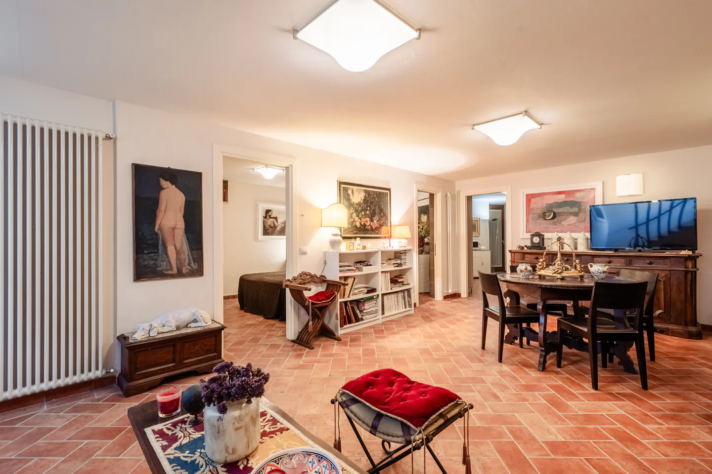 A living room with terracotta floors, white walls, and a mix of antique and modern furniture.