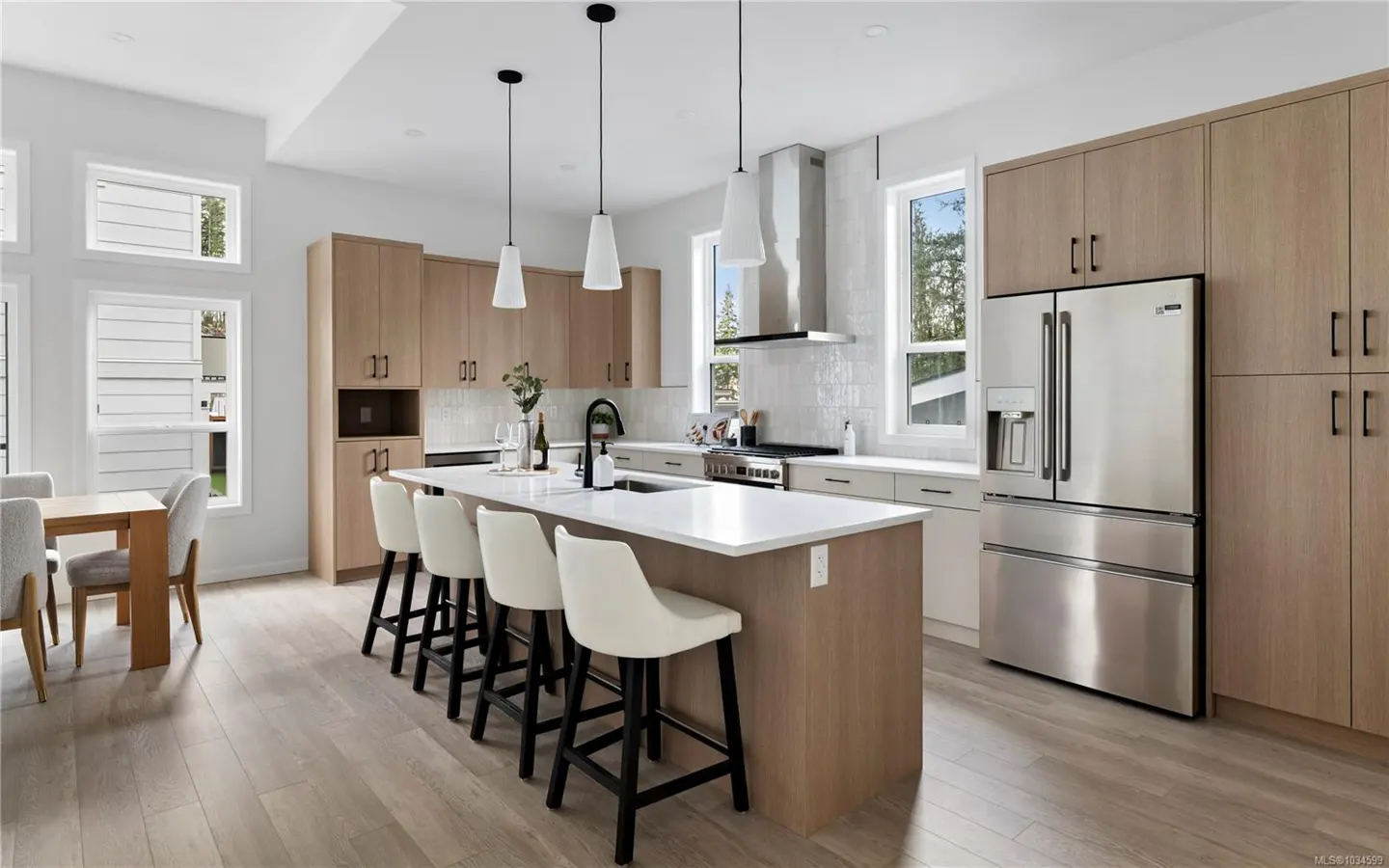 Bright, modern kitchen with wood cabinets, stainless steel appliances, and a large island with white countertops and seating.