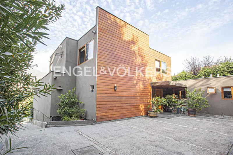 Exterior view of a modern two-story house with wood and gray stucco siding, and an Engel & Völkers logo.