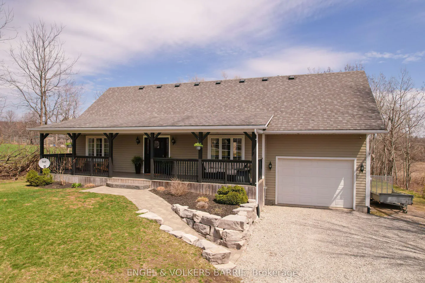 Tan house with a dark brown porch and a white garage door. A stone path leads to the front door.