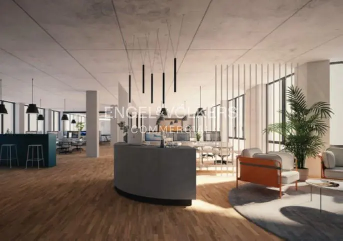 Open office space with wood floors, a gray reception desk, and modern lighting fixtures. Windows provide natural light.