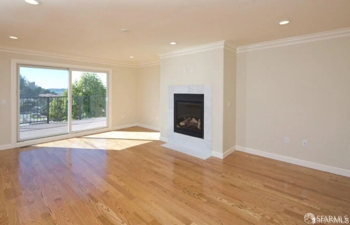 Bright living room with hardwood floors, a marble fireplace, and sliding glass doors to a balcony with a view.