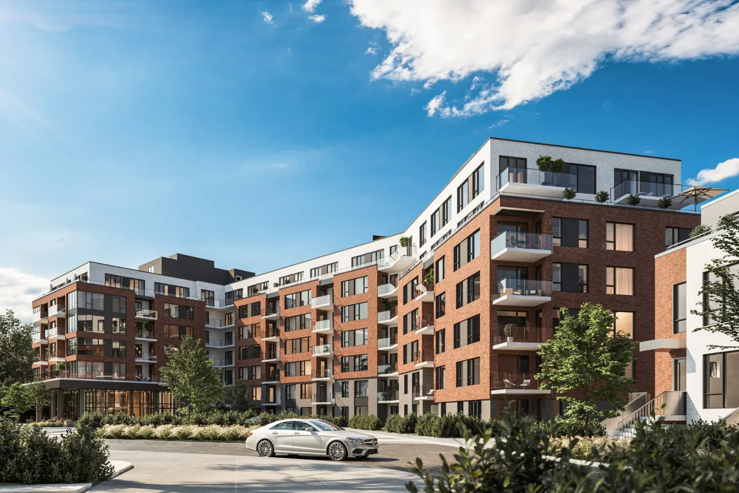 Exterior view of a modern brick apartment building with balconies, a white car parked in front, and a blue sky.