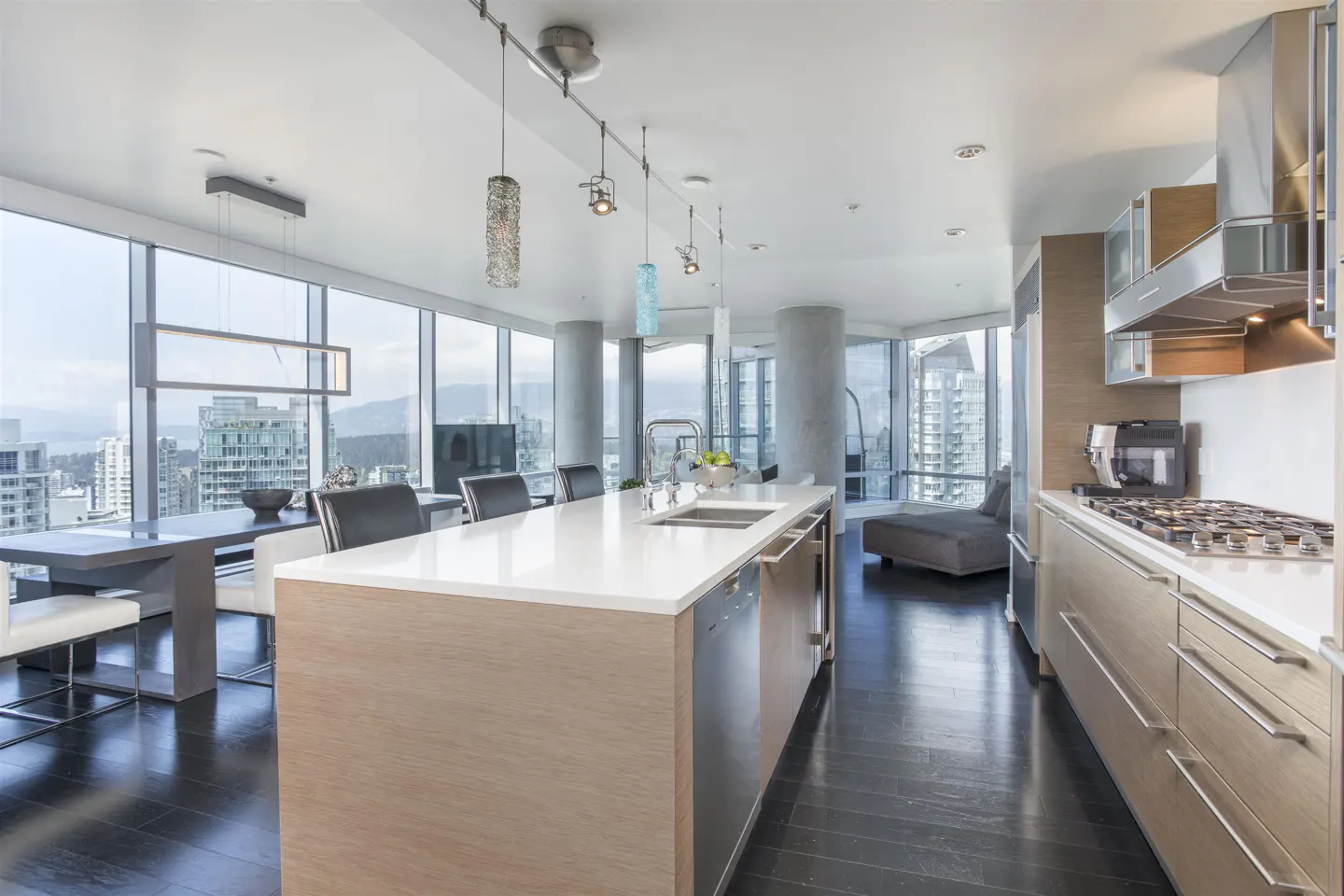 A modern kitchen with a large island, stainless steel appliances, and floor-to-ceiling windows with a city view.