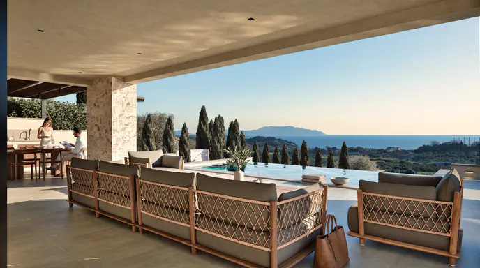 Covered patio with modern outdoor furniture overlooking an infinity pool, lush trees, and a distant sea view at sunset.