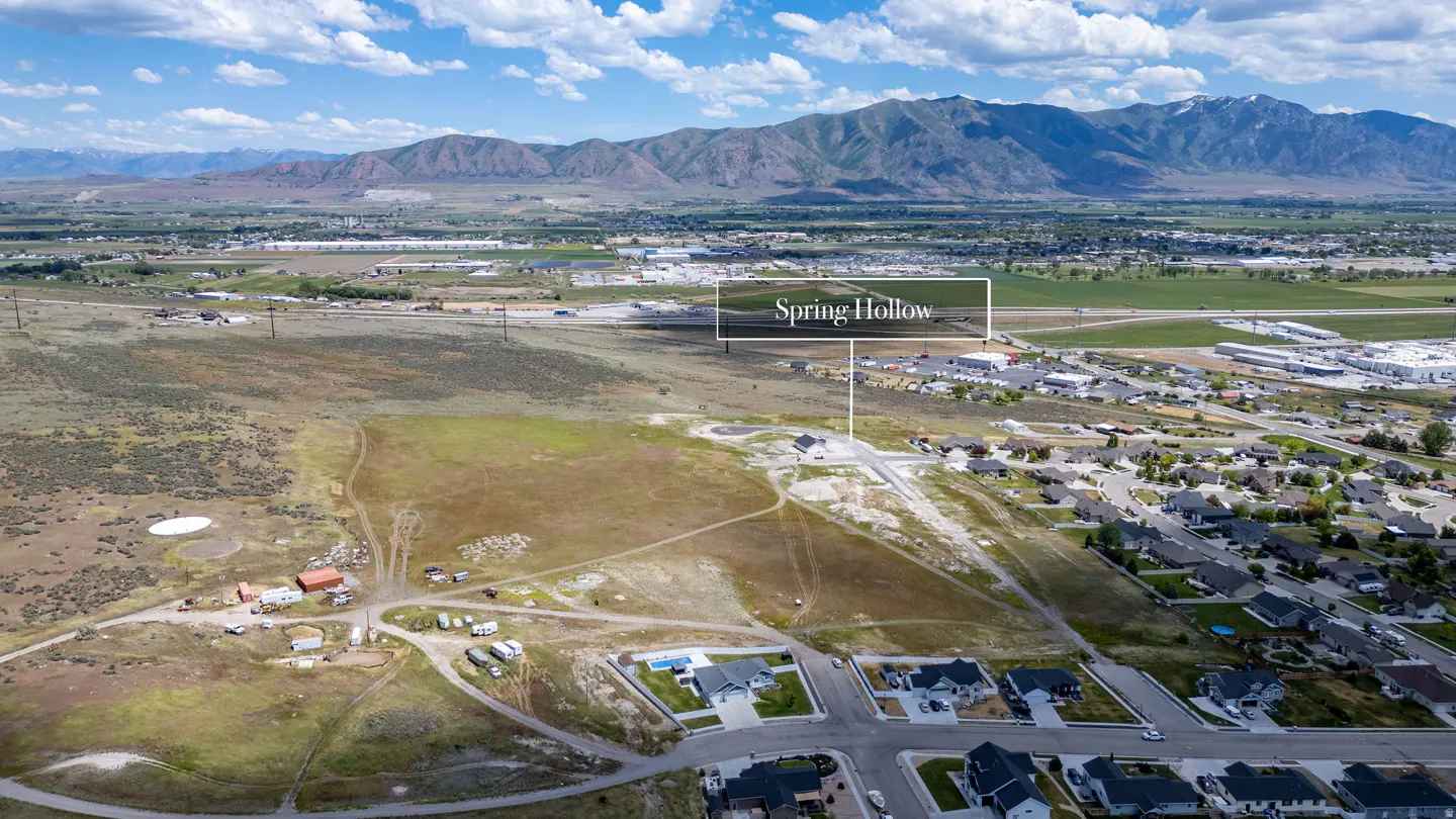 Aerial view of Spring Hollow development site with surrounding residential homes, open land, and distant mountain range.