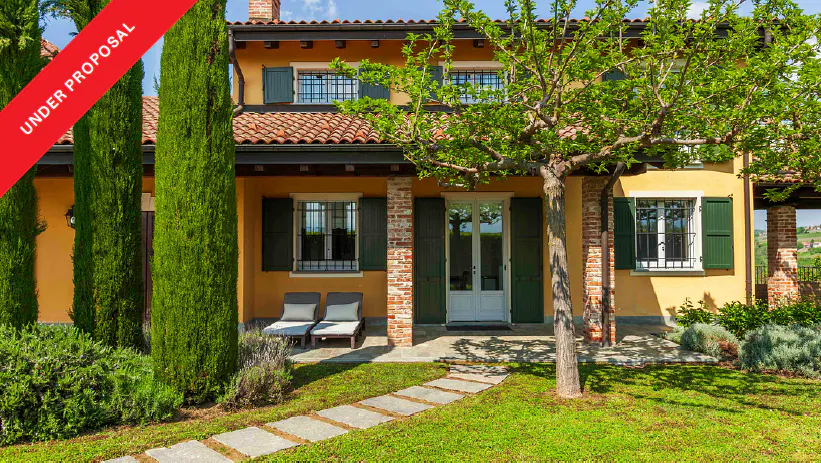 Exterior of a yellow two-story house with green shutters and a red "Under Proposal" banner. A stone path leads to the front door.