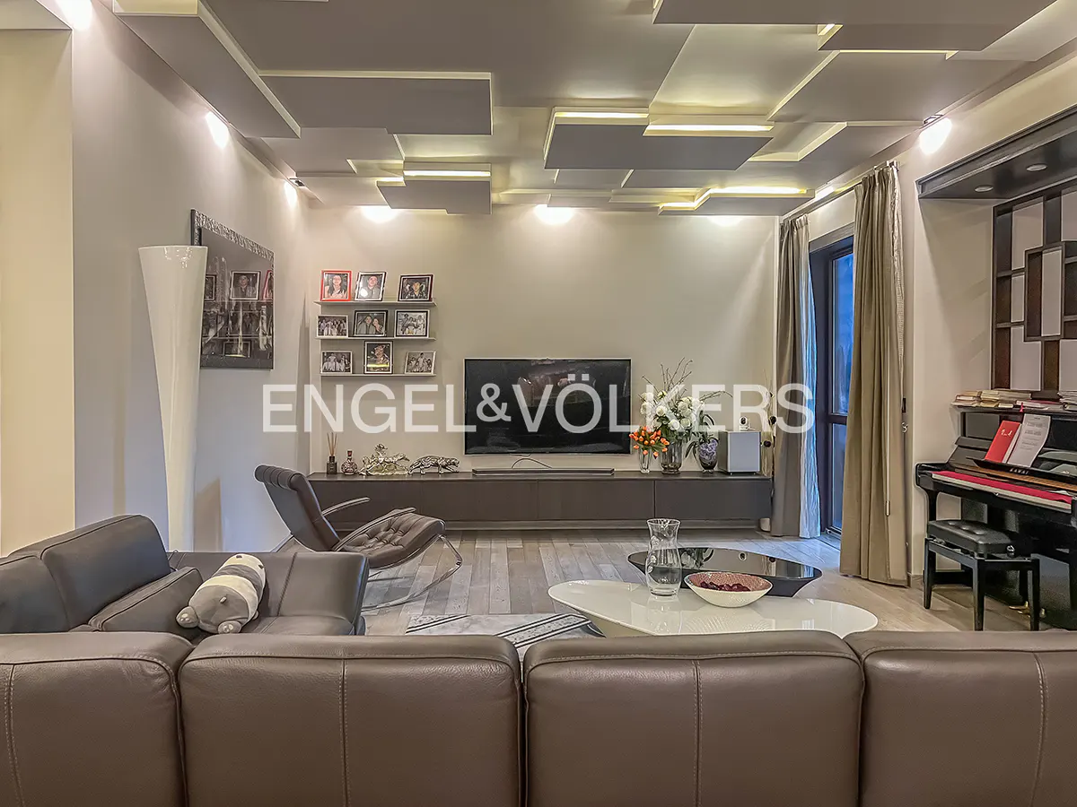 Living room with brown leather sofa, TV, piano, and modern ceiling with lights.