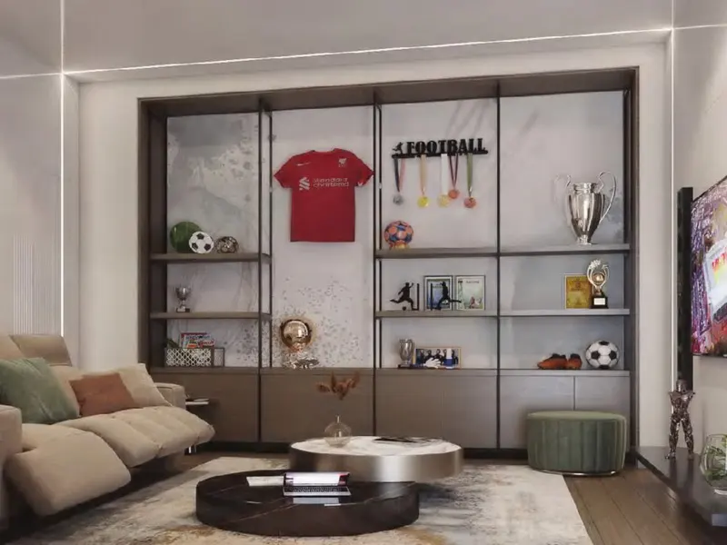 Living room with a beige sofa, round tables, and a large shelving unit displaying football memorabilia.