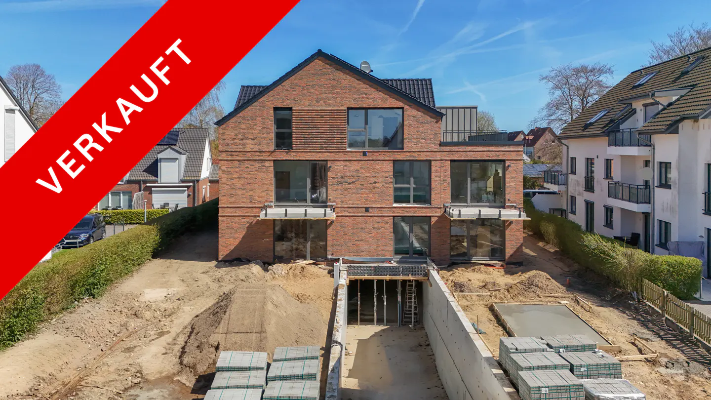 A three-story brick house with a red "VERKAUFT" banner, indicating it's sold. Construction is visible in the front yard.