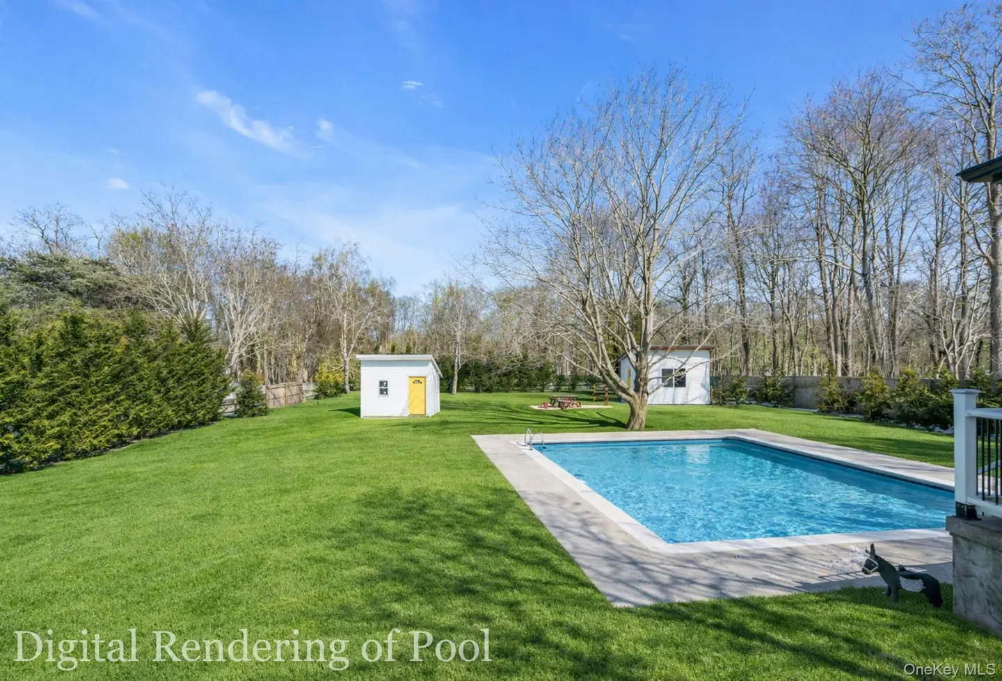 A backyard with a pool, green grass, trees, and two white sheds under a blue sky.