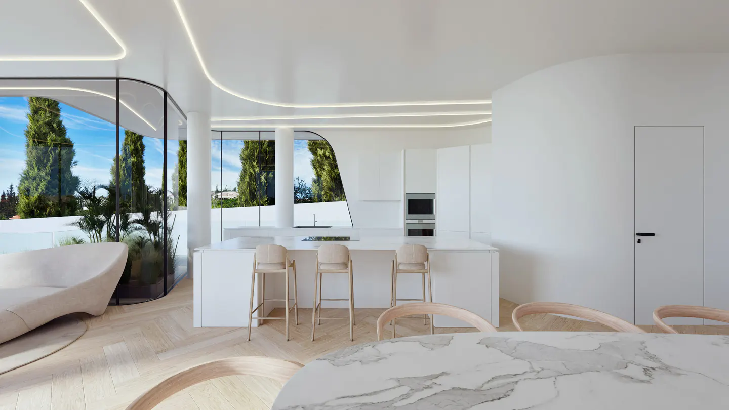 Bright, modern kitchen with white cabinets, island with stools, and marble table. Large windows offer views of trees and blue sky.