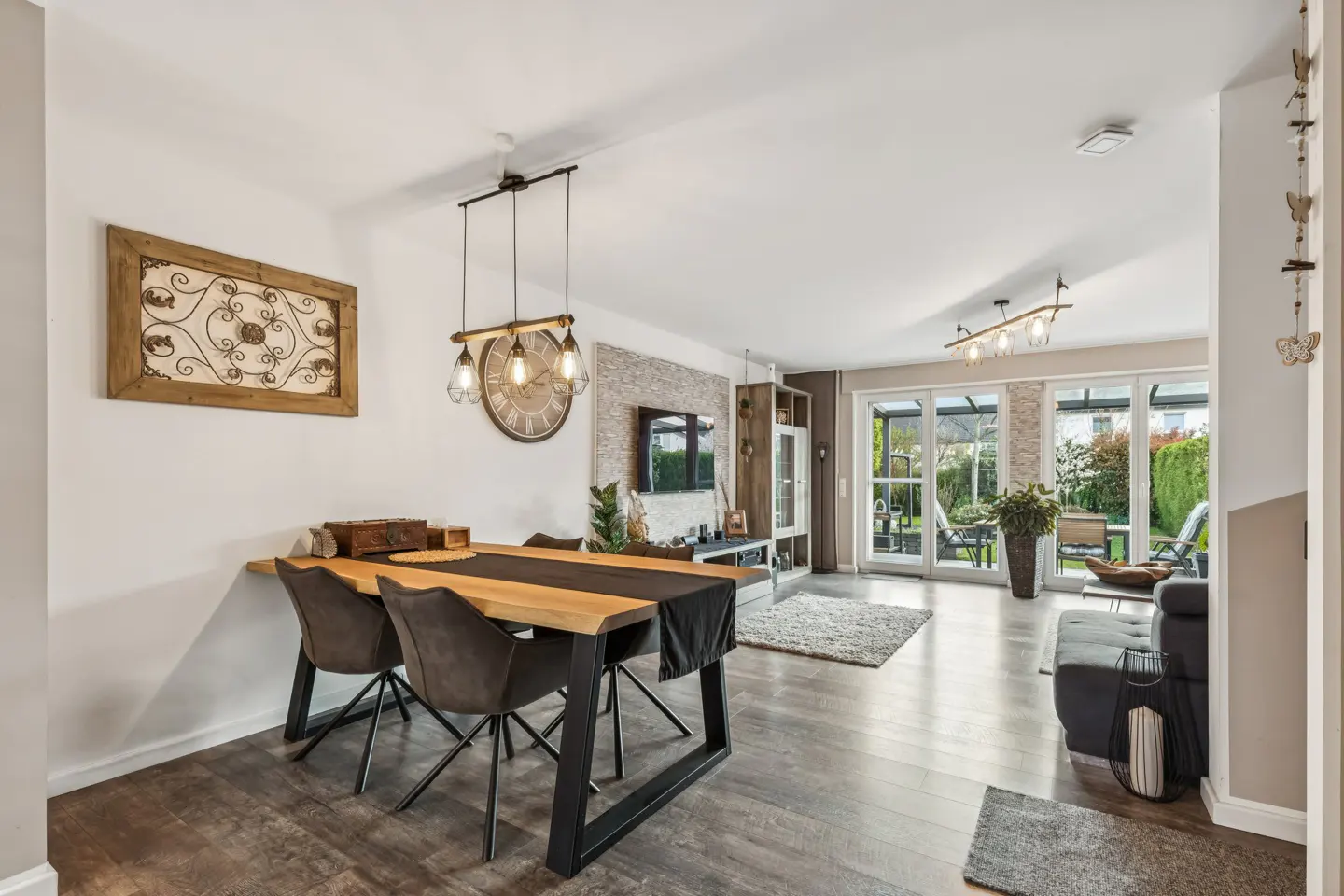 Open-concept living and dining area with wood floors, table, chairs, and a view of the backyard through sliding glass doors.