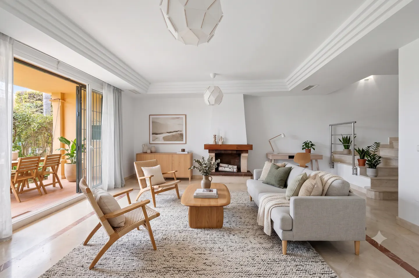 Bright living room with a light gray sofa, two wooden armchairs, a coffee table, fireplace, and patio access.