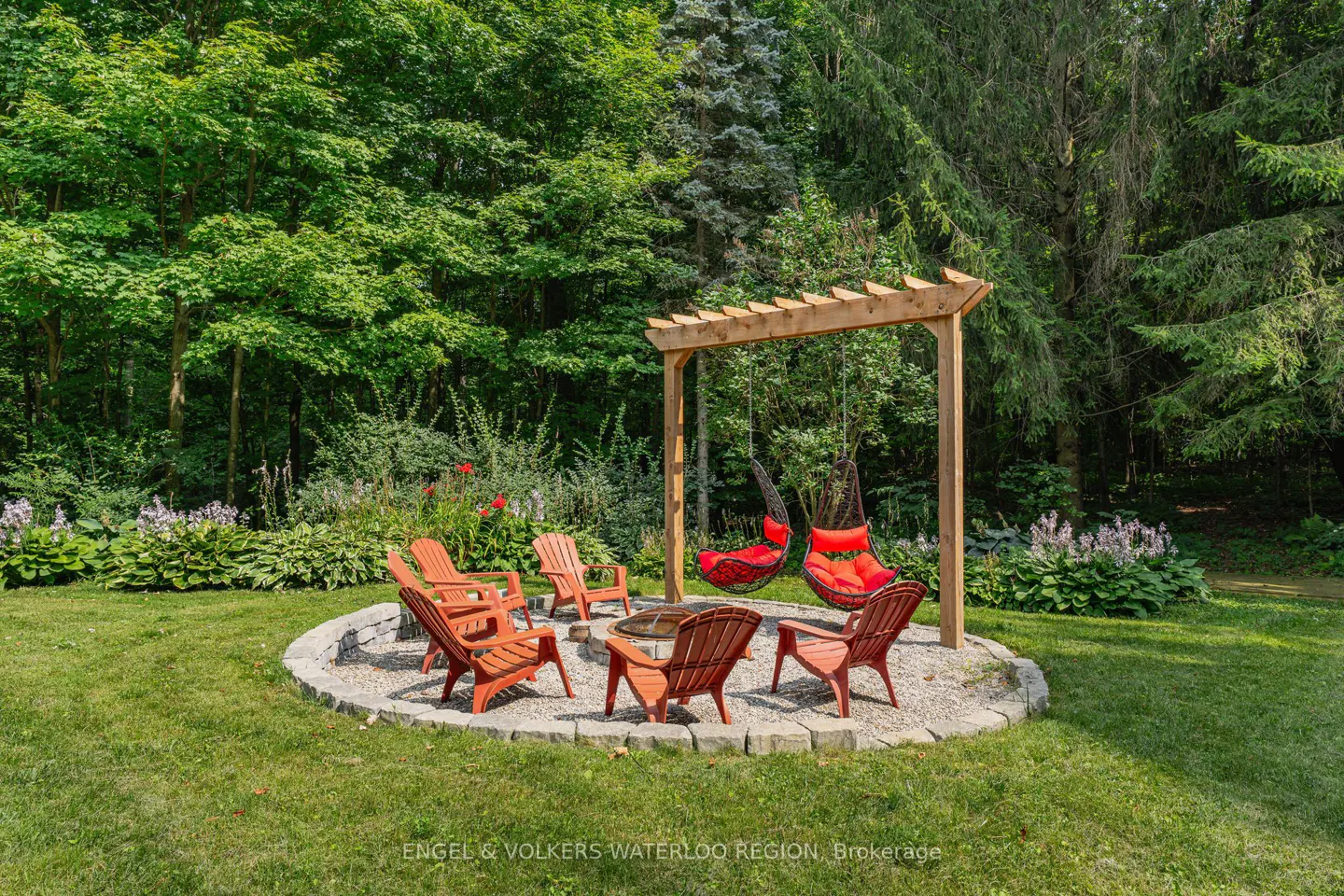 Outdoor living space with orange Adirondack chairs around a fire pit and two hanging chairs under a wooden pergola, surrounded by lush greenery.