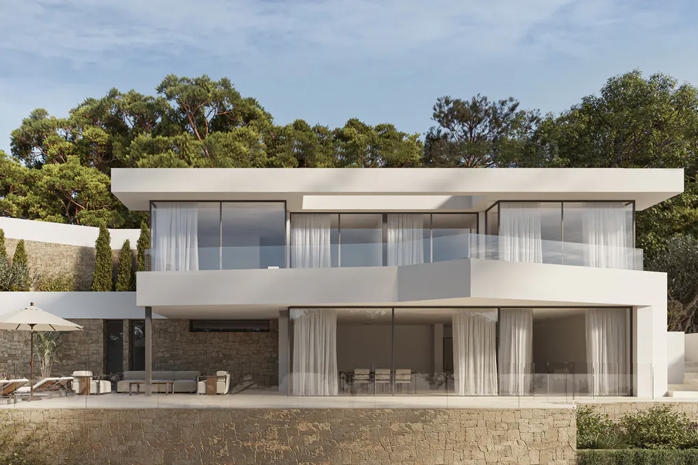 Two-story modern white house with large windows and a stone retaining wall. Trees are visible in the background.
