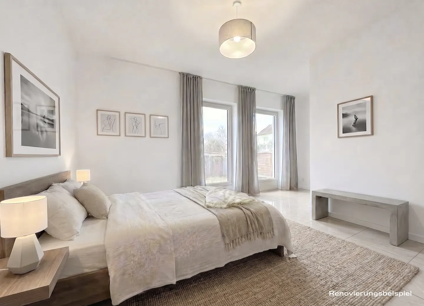 Bright bedroom with a bed, nightstand, lamp, rug, bench, and framed art. Gray curtains hang by the windows.