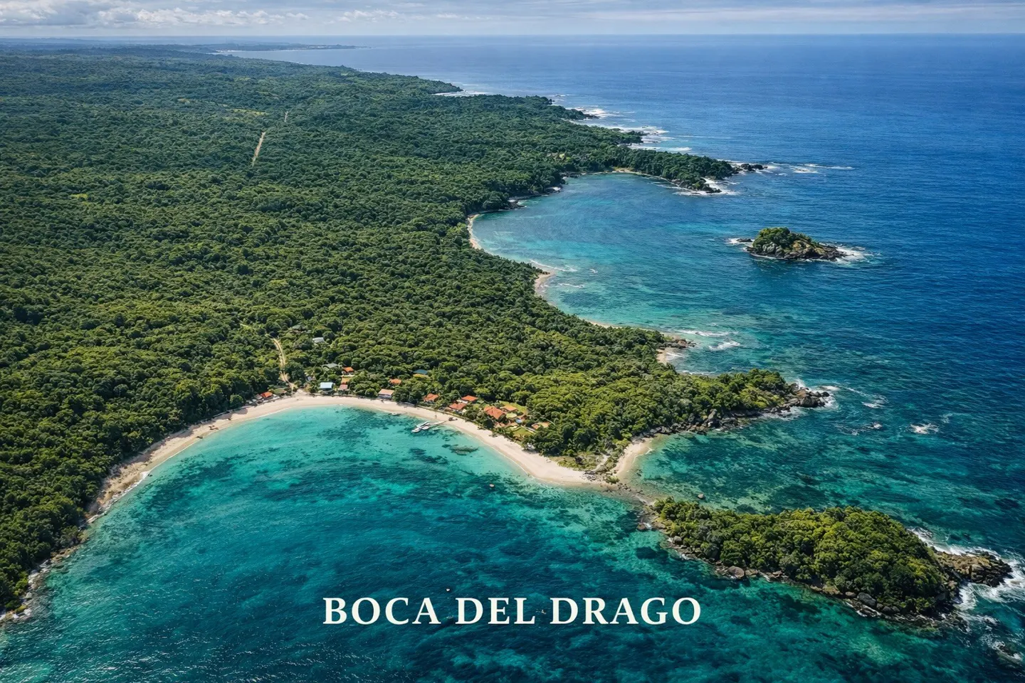 Aerial view of Boca del Drago, Panama, featuring lush green forest, turquoise water, sandy beach, and small buildings.