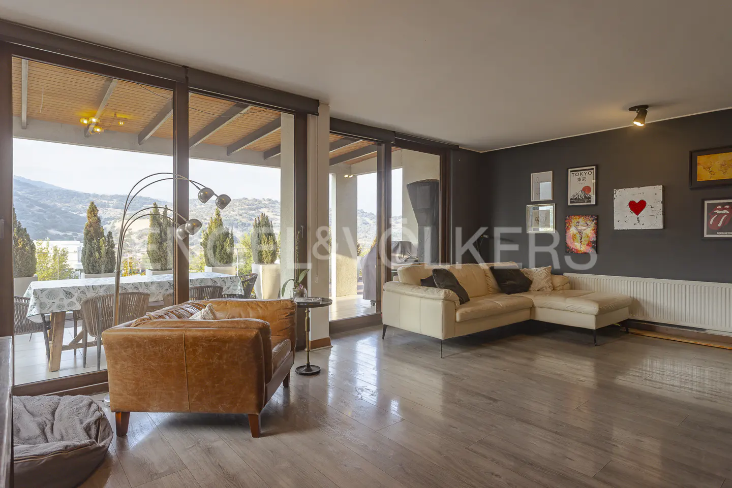 Living room with a brown leather armchair, a beige sectional sofa, and a view of mountains through sliding glass doors.