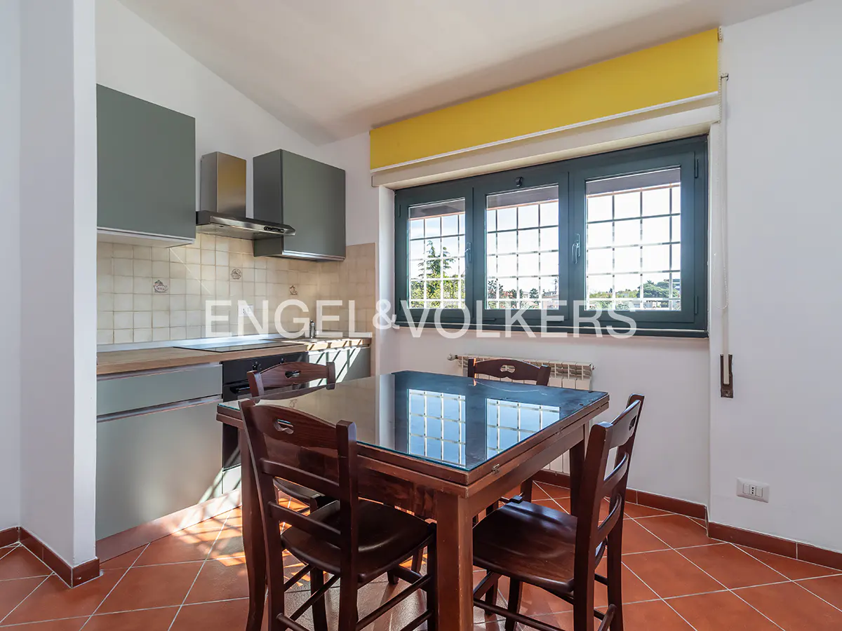A kitchen with gray cabinets, a dark wood table, and a large window with a yellow valance.